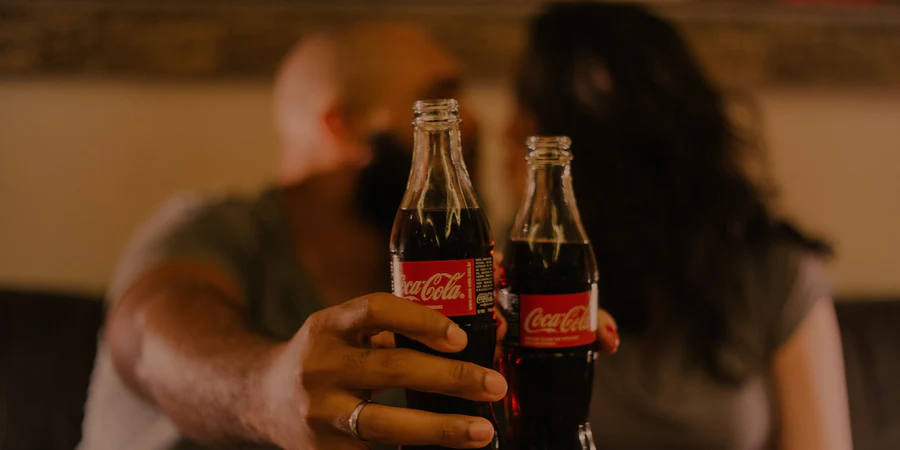 Two_people_cheersing_with_Coca-Cola_bottles_900x